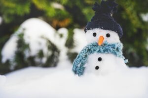 Adorable snowman with hat and scarf in a snowy outdoor setting, creating a festive winter scene.